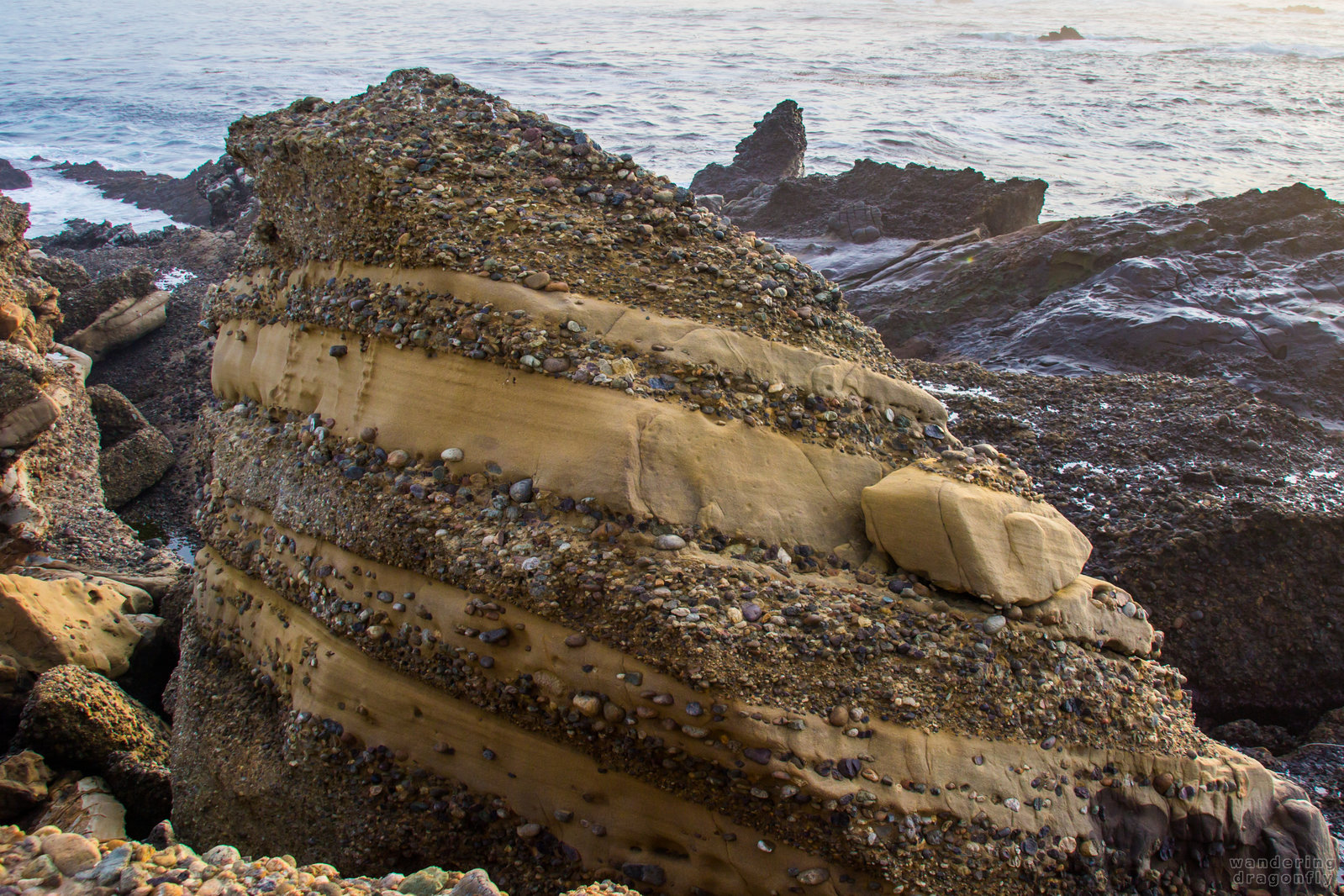 Layered rock -- cliff, gravel, ocean, rock, water