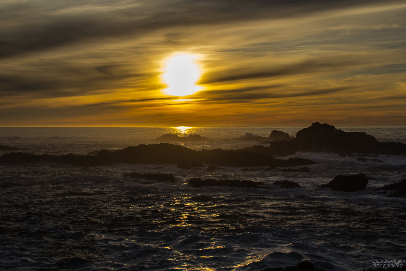Descending sun -- cloud, ocean, rock, sun, sunset, water, wave