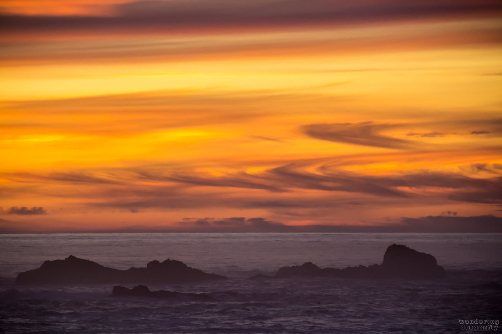 Twilit cloud-swirls -- black, cloud, ocean, orange, rock, sunset, water, yellow