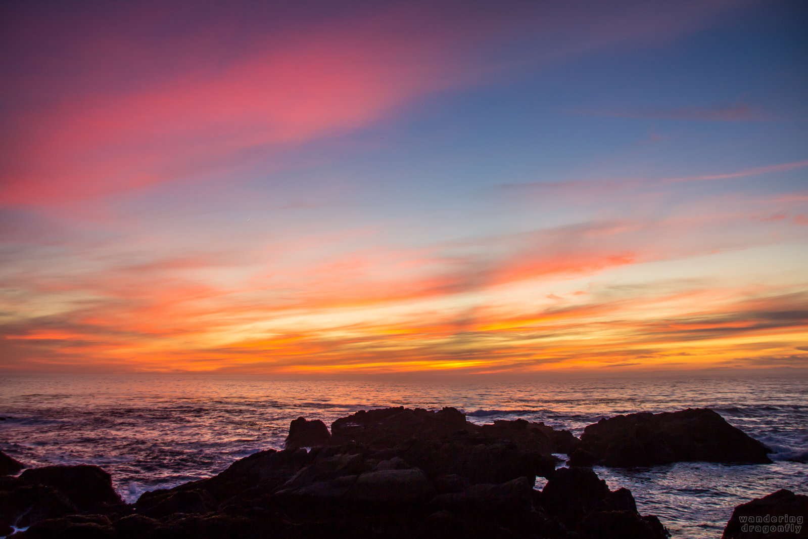 Amazingly colorful patches of the sunset -- cliff, cloud, ocean, orange, pink, rock, sunset, water, yellow