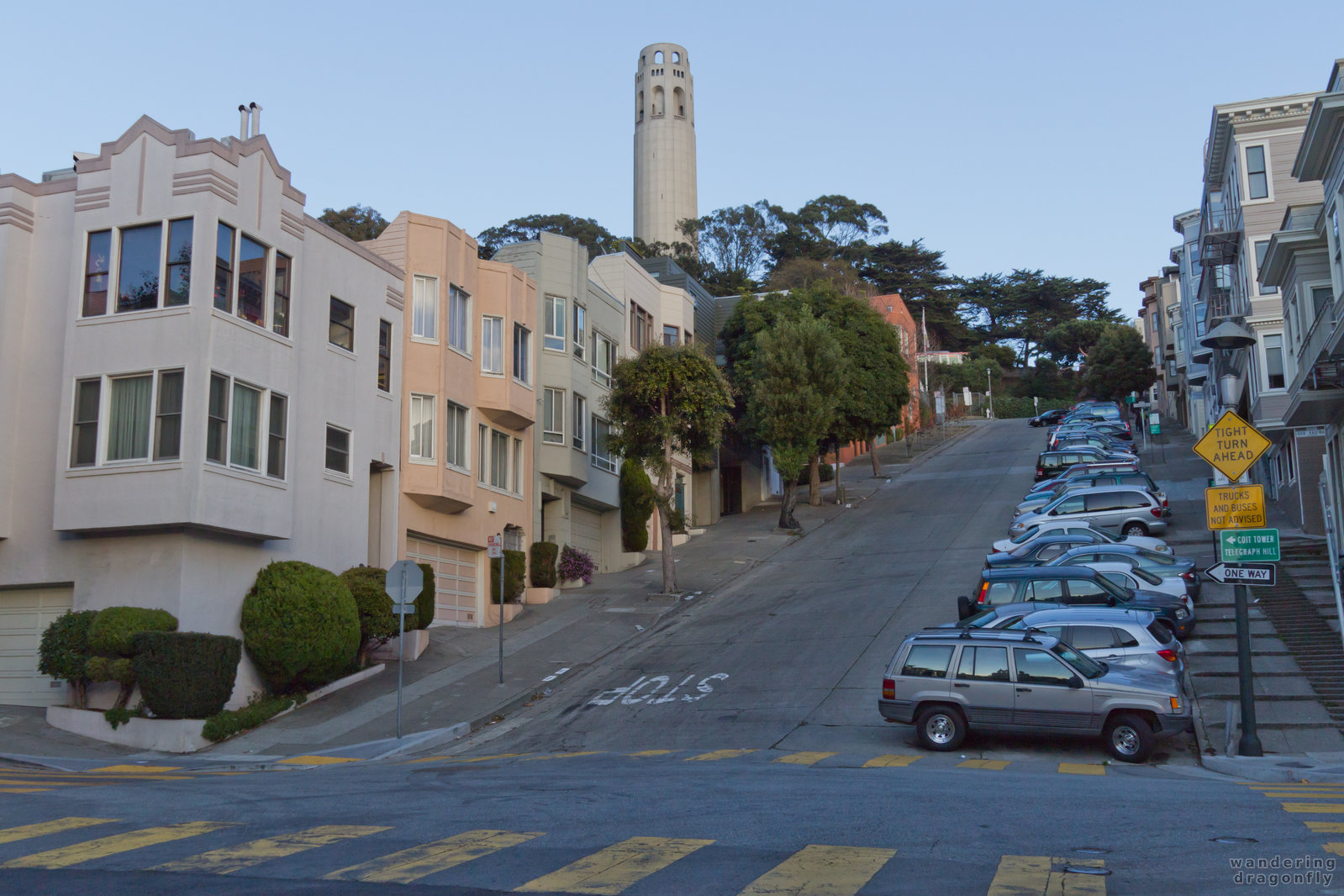 The steep Filbert Street heads up to the Coit Tower -- building, car, street, street sign, tower