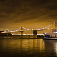 In the background the Bay Bridge can be seen with the lights of Oakland and the dark patch of the Yerba Buena Island.